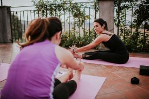Deux femmes assises au sol dans un cours de yoga aoratif dans l'établissement Merumalia Wine Resort, à Frascati