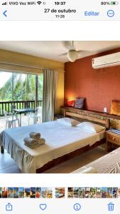 - une chambre avec un grand lit et un balcon dans l'établissement Pousada Luar da Praia, à Imbassaí