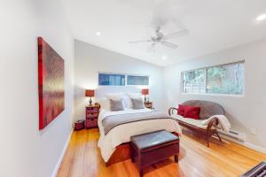 a white bedroom with a bed and a chair at River Paradise in Guerneville