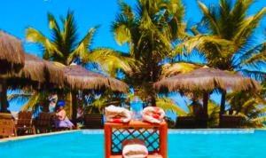 um resort com uma piscina com palmeiras em Pousada Luar da Praia em Imbassaí