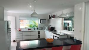 a kitchen with white cabinets and a black counter top at Venha se hospedar no Paraíso de Guarajuba in Camaçari
