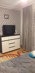 ein Wohnzimmer mit einem TV und einer weißen Kommode in der Unterkunft MamaiaApart in Lupeni