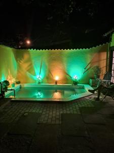 una piscina por la noche con luces verdes en Do charme, en Búzios
