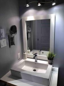 La salle de bains est pourvue d'un lavabo blanc et d'un miroir. dans l'établissement Condo entier, fully equiped pool and Spa only in summer, à Mont-Tremblant