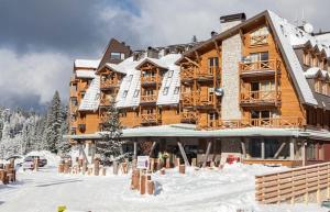 a large wooden building with snow on it at Apartman 105 Vucko Jahorina in Jahorina