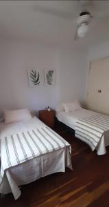 two beds in a room with white walls and wood floors at Departamento céntrico en San Martín, amplio, con aire acondicionado y cochera privada in San Martín