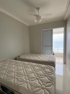 een slaapkamer met 2 bedden en een plafondventilator bij Lindo Apto Pé na areia Frente para Mar in Praia Grande