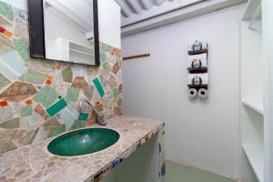 a bathroom with a green sink and a mirror at EcoHotel La Fortuna 