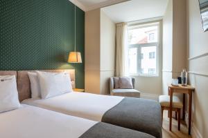 Habitación de hotel con cama y silla en Rossio FLH Suites en Lisboa