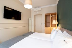 a bedroom with a large bed with a tv on the wall at Rossio FLH Suites in Lisbon