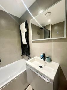 a white bathroom with a sink and a tub and a mirror at Anchor's Away in Poole