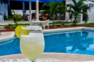 una bebida sentada en una mesa junto a una piscina en Hotel Maria de Lourdes, en Cancún