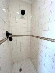 baño de azulejos blancos con ducha y ventilador en Hostal Sky Crest en Clearwater