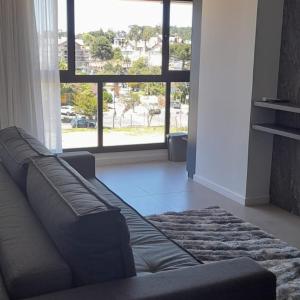 a living room with a couch and a large window at Apartamento Central em Canela in Canela