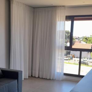 a living room with a couch and a large window at Apartamento Central em Canela in Canela +18 photos