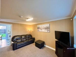 a living room with a leather couch and a flat screen tv at Taylor Close in Fishtoft