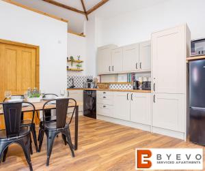 a kitchen with white cabinets and a table and chairs at ByEvo Oswestry Barn - Quirky romantic retreat or cosy contractor base in Oswestry