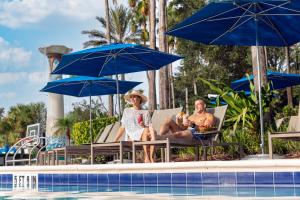 dos mujeres sentadas en sillas junto a una piscina con sombrillas en Omni Orlando Resort at Championsgate en Kissimmee