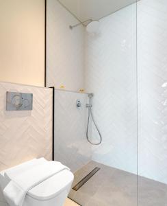 a bathroom with a toilet and a glass shower at LIV The City Suites ADULTS ONLY in Larnaka
