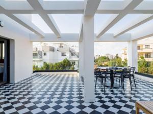 a patio with a table and chairs on a checkered floor at LIV The City Suites ADULTS ONLY in Larnaka