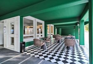 a green room with chairs and tables on a checkered floor at Maestro St Lazar Apartments in Larnaca