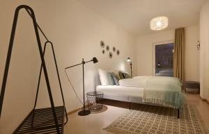 a white bedroom with a bed and a lamp at Argentieri City Loft in Bolzano