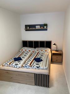 Una cama con una manta con una mesita de noche en Apartmán Emilka, en Janov nad Nisou