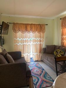 ein Wohnzimmer mit einem Sofa und einem Fenster in der Unterkunft Sasha’s Holiday Home Oistins Barbados in Christchurch