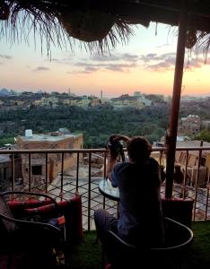 a woman taking a picture of the sunset from a balcony at Al Misfah Hospitality Inn in Misfāh