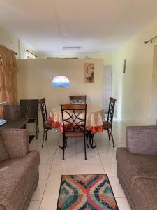 ein Wohnzimmer mit einem Tisch, Stühlen und einem Sofa in der Unterkunft Sasha’s Holiday Home Oistins Barbados in Christchurch