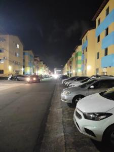 uma rua com carros estacionados num parque de estacionamento à noite em Apartamento Tupy I - Turu em São Luís