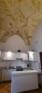 cocina con armarios blancos y techo de piedra en I Balconi sul Duomo, en Lecce