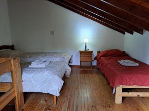 a room with two beds and a table with a lamp at La Casita del Bosque in Ushuaia