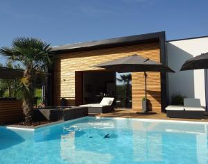 a swimming pool with an umbrella next to a house at Splendide Villa ESTEVE piscine démesurée proximité Sarlat in Sainte-Mondane