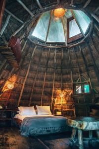 a bed in a thatched room with a window at Ikal Tulum Hotel in Tulum