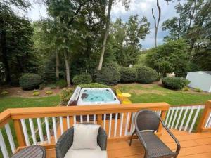 una terraza con 2 sillas y una piscina en Lux Family Xcape with HotTub Fireplace Deck BBQ en Silver Spring