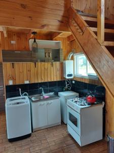 a kitchen with white appliances in a wooden cabin at Cabaña Don Flako in Coihaique