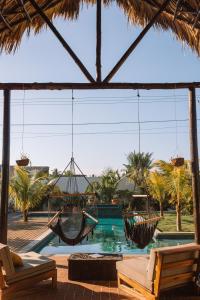 un patio con hamacas y una piscina con palmeras. en Casa Zala en El Paredón Buena Vista