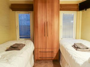 a bedroom with two beds and a wooden cabinet at Washburn Lodge in Harrogate