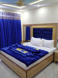 a bedroom with a large bed with blue curtains at Hotel new royal palace in Lahore