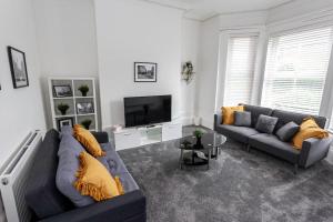 a living room with two couches and a television at Spacious Comfortable house close to Etihad+parking in Manchester