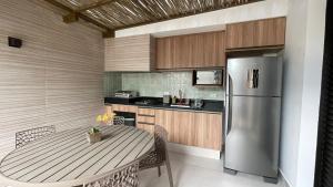 a kitchen with a table and a stainless steel refrigerator at Flores de Juquehy in Praia de Juquehy