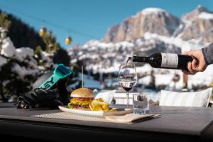 a person pouring a glass of wine over a hamburger and chips at Hotel Arkadia - "Adults Only" in Corvara in Badia