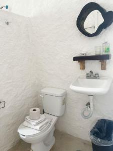 La salle de bains blanche est pourvue de toilettes et d'un lavabo. dans l'établissement Hotel Lifestyle KB Holbox, à Holbox