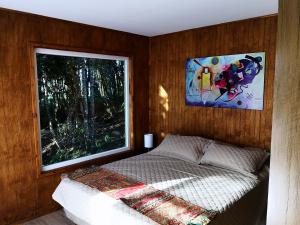een slaapkamer met een bed en een groot raam bij Cabañas Mirador Los Avellanos in Castro
