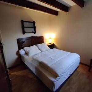 a bedroom with a white bed with a light on it at Maison cosy proche de font romeu in Latour-de-Carol
