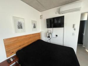 a bedroom with a bed and a tv on the wall at Luminoso Depto 40 metros NUEVO. Excelente Ubicacion Zona Sur. in Remedios de Escalada