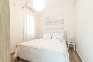 a white bedroom with a large bed with white sheets at Boutique Apartment with ParkView in Heraklio Town
