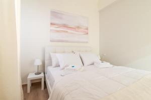 a white bedroom with a large white bed with white pillows at Boutique Apartment with ParkView in Heraklio Town