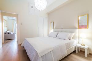 a white bedroom with a large white bed and a chandelier at Boutique Apartment with ParkView in Heraklio Town
